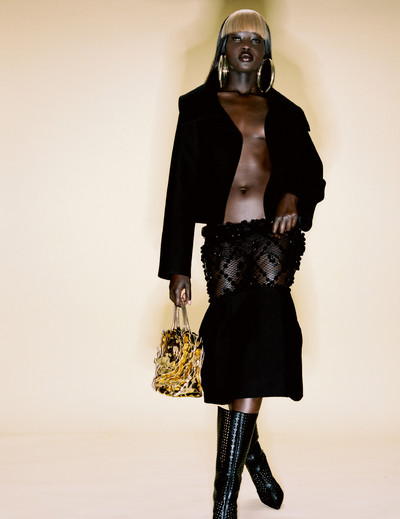 Aweng wears jacket, dress (worn as skirt) and bag by Valentino, boots by Alaïa, and stylist’s own earrings. - © System Magazine