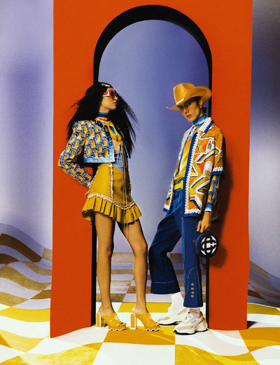 Anita wears gold plated Casa hairclip, 18k gold plated red and white acetate frames, printed silk scarf blouse, leather frill slip dress, embroidered night arches jacket, and citrus leather platform mule. Paul wears citrus stetson cowboy straw hat, printed silk scarf blouse, printed short sleeve cuban collar silk shirt, yellow cowboy leather belt, blue flare wool silk mix trousers, blue and white round monogram leather bag, and off-white suede Atlantis sneaker. - © System Magazine