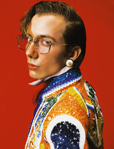 Paul wears 18k gold metal frames, white and gold resin dome earrings, panelled leather overshirt, embroidered jacket, and white cotton shirt, all by Casablanca. - © System Magazine