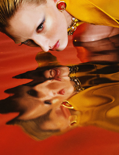 Maggie wears red and gold resin dome earrings, laurel long charm and chain necklace, and citrus lapel jacket, all by Casablanca. - © System Magazine
