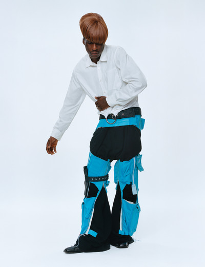 Momentum. Martine Rose & Tamara Rothstein. - © Darrell wears ring-pull shirt, black jersey trousers, blue leather chaps, wide leather belt, and black leather leg pouch, all Autumn/Winter 2016, and black leather brogues, Spring/Summer 2020., System Magazine