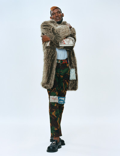 Momentum. Martine Rose & Tamara Rothstein. - © Nigel wears faux-fur coat, striped shirt, patch camouflage trousers, and beer-mat belt, all Fall/Winter 2018, and ring-pull loafers, Spring/Summer 2023., System Magazine